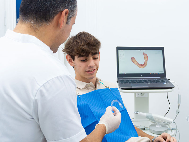 Dentista mostra apparecchio trasparente a un ragazzo