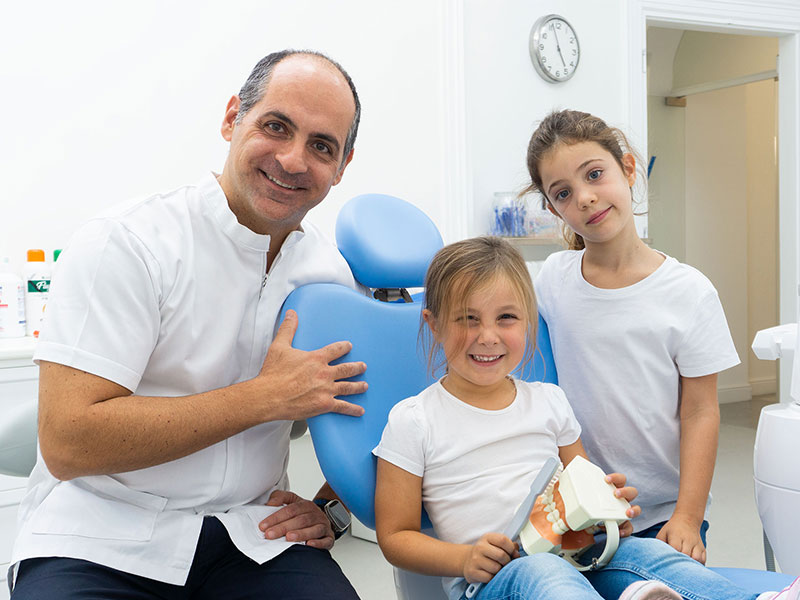 Dentista con bambine che sorridono